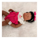 Reborn baby doll Emily, featuring closed eyes, African American skin tone, curly black hair, and a pink dress with cherry design.