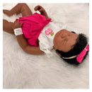 African American full silicone reborn baby doll, Emily, with closed eyes, wearing a white shirt and pink shorts.