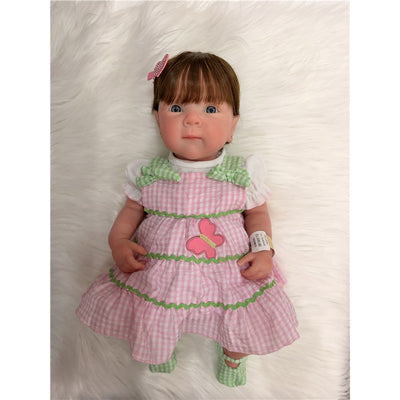 Reborn Baby Doll Bettie with full silicone body, wearing a pink and green checkered dress with a butterfly design.