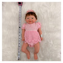 Reborn Baby Doll Vivienne, featuring a full silicone body, dressed in a pink outfit with lace detailing.