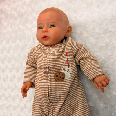 Reborn baby doll with blue eyes wearing a striped onesie featuring a milk and cookie design.