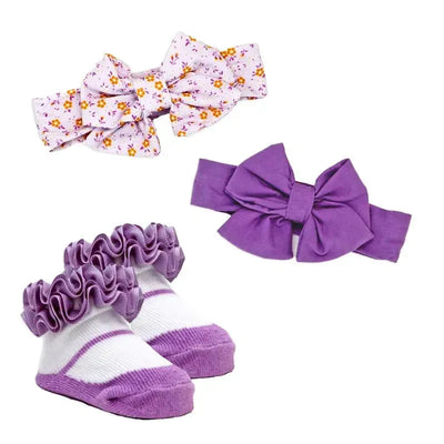 Three-piece lilac floral headband and sock set including a floral bow headband, a solid purple bow headband, and frilly purple and white socks.