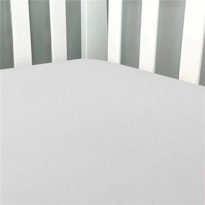 Solid grey flannel crib sheet fitted snugly on a crib mattress, surrounded by white crib slats.