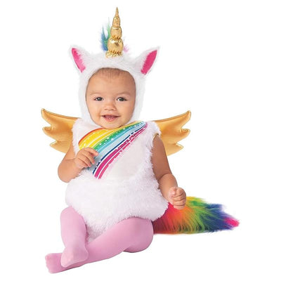 Toddler wearing a fluffy white unicorn costume with a rainbow sash and gold wings, smiling brightly.