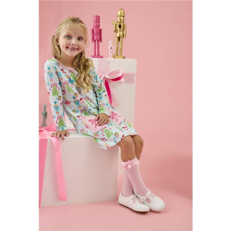 Knee-high pink socks with lace and bows worn by a girl in a colorful, festive dress, sitting on a pedestal with decorations.