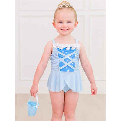 Toddler girl wearing a crystal blue dress-up swimsuit with ruffles and a tiara, holding a light blue bucket.