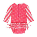 Hot pink long sleeve one-piece rash guard for toddlers, featuring white polka dots and striped sleeves, with a back zipper and ruffled detail.