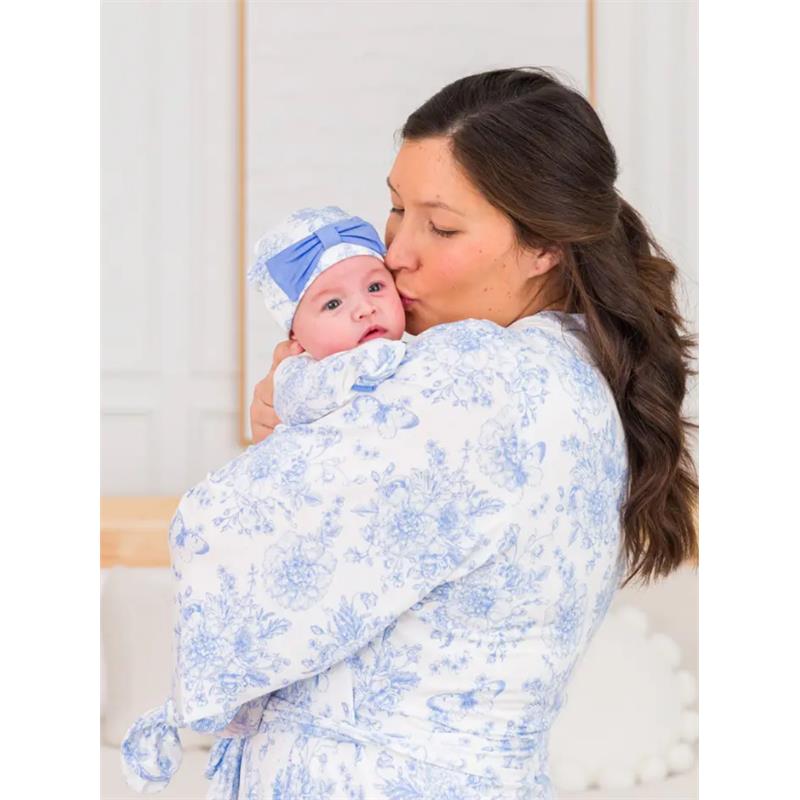 Mom kisses her baby in a floral-patterned blue and white maternity robe, while the baby wears a matching hat.