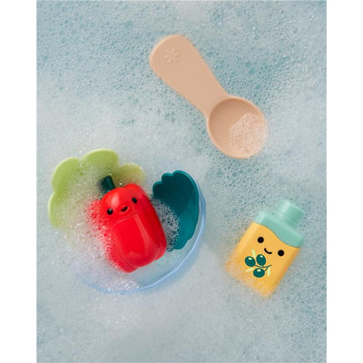 Brightly colored bath toys including a red pepper, green and blue bowls, and a yellow bottle, surrounded by bubbles.