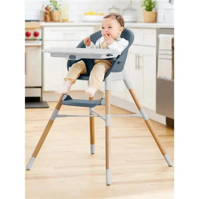 EON 4-in-1 high chair in slate blue with a smiling baby wearing striped overalls, sitting at a kitchen table.