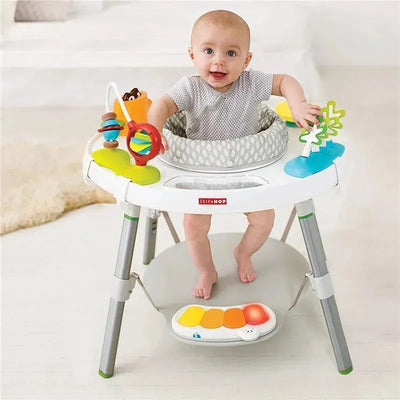 Baby in a Skip Hop Explore and More Activity Center, smiling while playing with colorful toys and a musical panel.