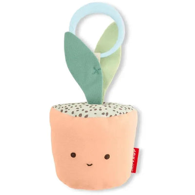 Soft fabric toy shaped like a smiling potted plant, featuring green leaves and a removable ring for attachment.