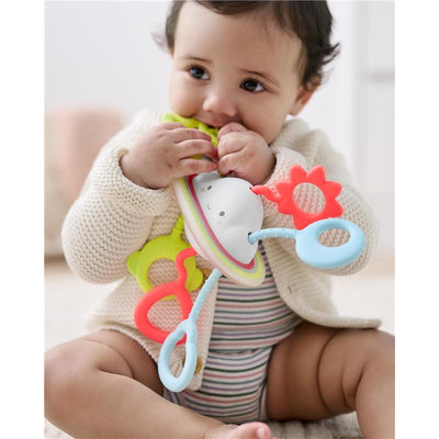 Baby enjoying the Skip Hop Silver Lining Cloud Pull & Play sensory toy, featuring colorful rings and a smiling cloud shape.