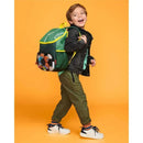 Big Kid Backpack by Skip Hop featuring a soccer design, carried by a smiling boy in casual attire against a bright orange background.
