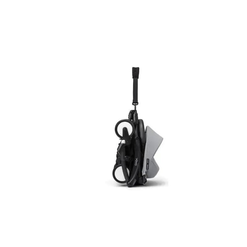 Stokke Yoyo³ stroller in a compact, folded position with a black frame and stone-colored fabric leg rest.