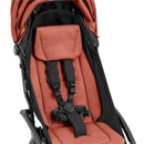 Compact Stokke Yoyo5 stroller in black frame, featuring a berry-colored seat with adjustable safety harness and headrest.