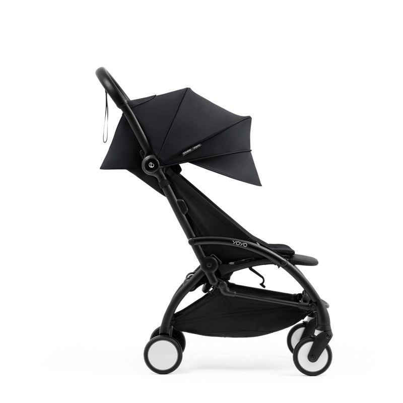 Compact black stroller with a black frame, featuring a foldable canopy and four wheels for easy maneuvering.