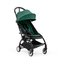 Stokke Yoyo5 compact stroller with a black frame and forest green seat, featuring a canopy and adjustable harness.
