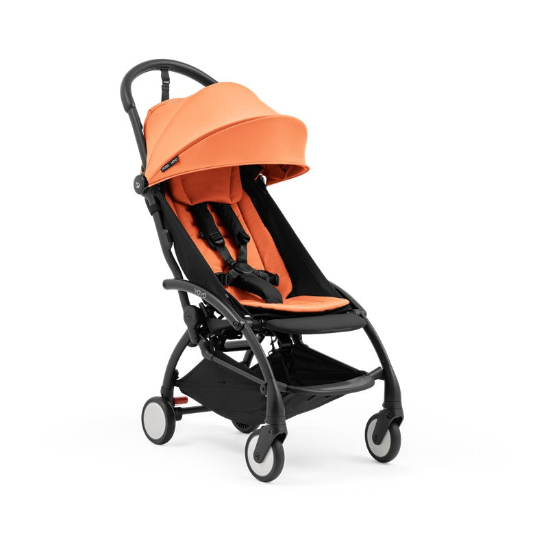 Compact Stokke Yoyo5 stroller with a black frame and peach fabric, featuring adjustable canopy and safety harness.