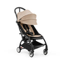 Compact Stokke Yoyo5 stroller with a black frame and taupe seat fabric, featuring a fully reclined seat and a large canopy.