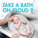 Boon PUFF+ Inflatable Baby Bather with a cheerful baby in a sink, enjoying bath time while being gently supported by a hand.
