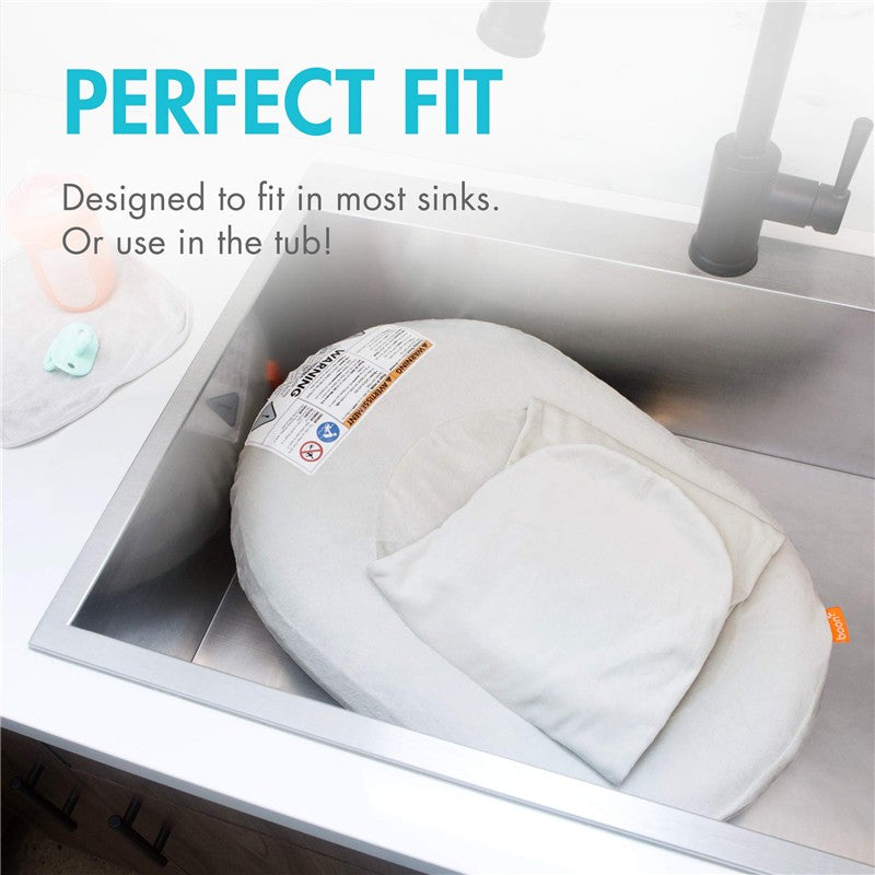 Inflatable Boon PUFF+ baby bather positioned in a sink, with tags indicating safety and use instructions.