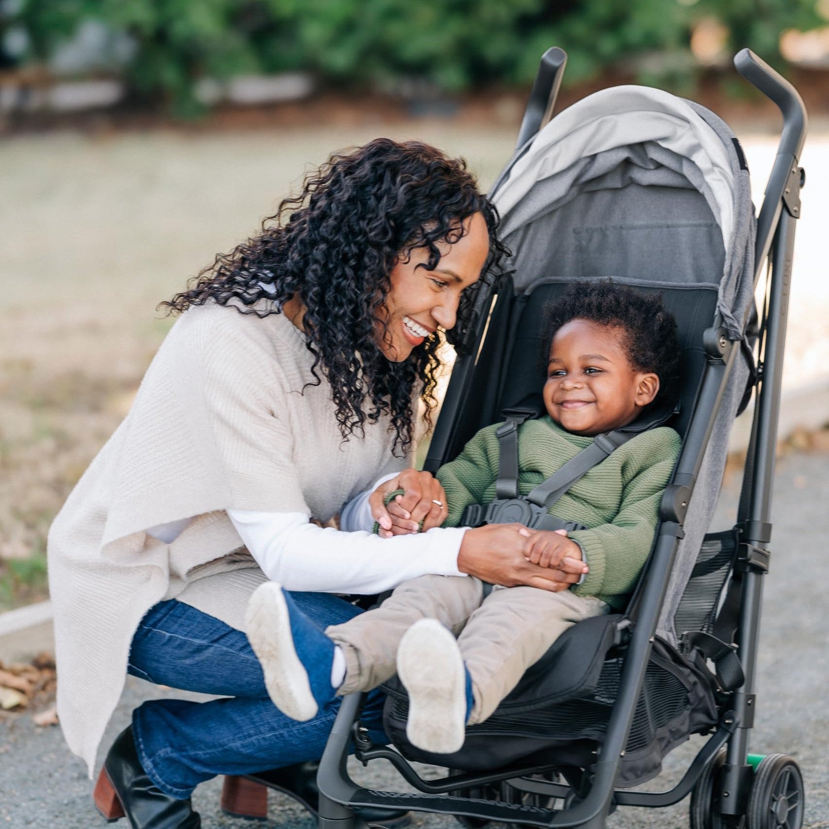 A smiling mother interacts with her happy toddler in a UPPAbaby G-Series stroller, showcasing its comfortable design.