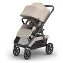 Uppababy Kona stroller in Sandstone Mélange with a beige fabric seat, adjustable canopy, and a sleek gray frame.