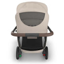 Uppababy Kona Stroller in Sandstone Mélange, featuring a mesh back, brown handlebar, and rear wheels with green and red buttons.