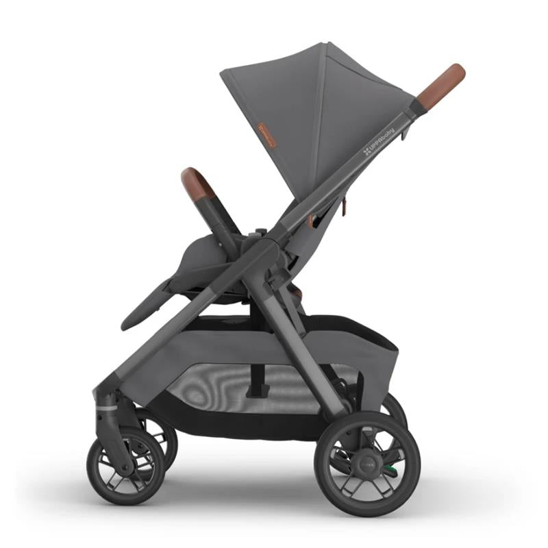 Uppababy Kona stroller in graphite color with a brown handlebar, featuring a reclining seat and spacious storage basket.