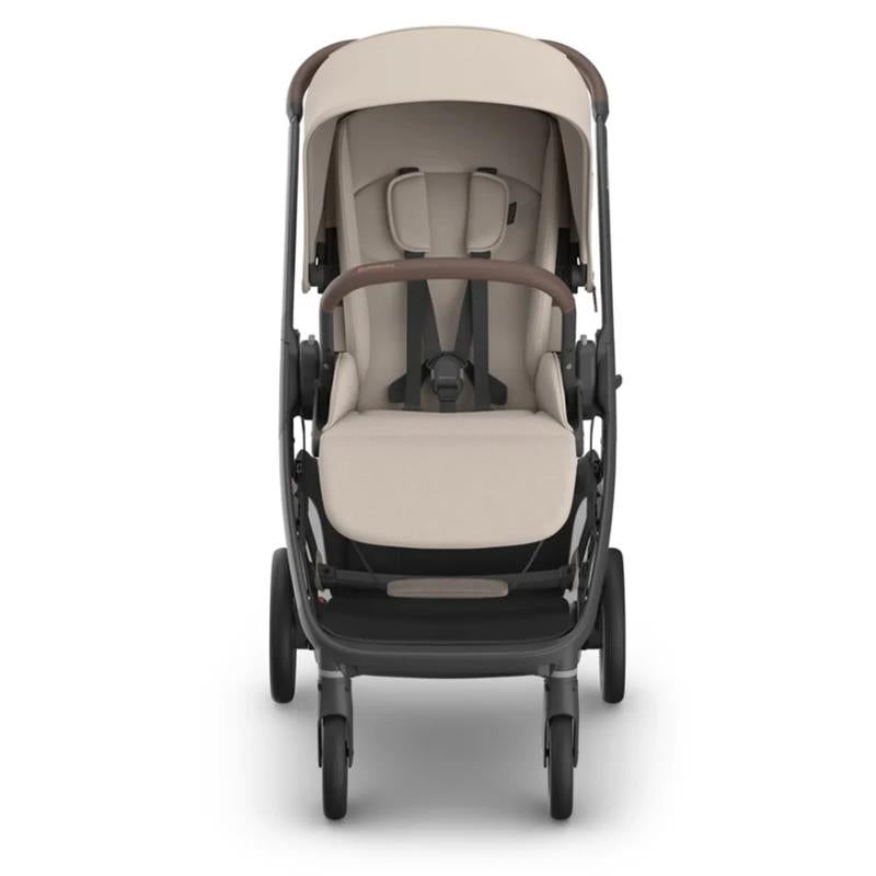 Uppababy Kona Stroller with beige seating and brown accents, featuring a harness and adjustable canopy, designed for infants.