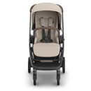 Uppababy Kona Stroller with beige seating and brown accents, featuring a harness and adjustable canopy, designed for infants.