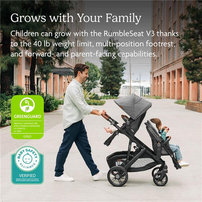 Uppababy Rumbleseat V3 in Meadow Green with a graphite frame, featuring a parent pushing it on a pathway with two children seated.