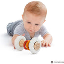 Baby playing with the Vulli Sophie La Girafe So Pure Totem Rattle, featuring a wooden center and colorful rings.