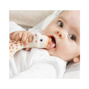 Baby holding a Vulli Sophie La Girafe teether, looking curiously at the camera with a finger in its mouth.