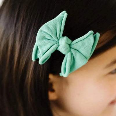 Baby Bling Bows mint green fabric hair bow clip on a child's brown hair