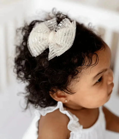 Baby girl with curly hair wearing a Baby Bling Bows princess ivory tulle hair clip